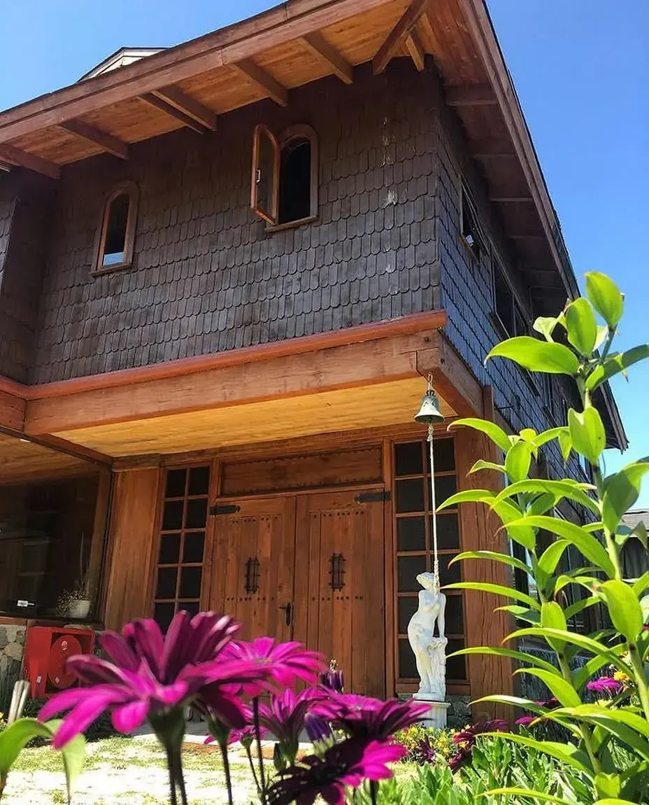 Fachada de madera de La Casona de Futrono con jardín y flores